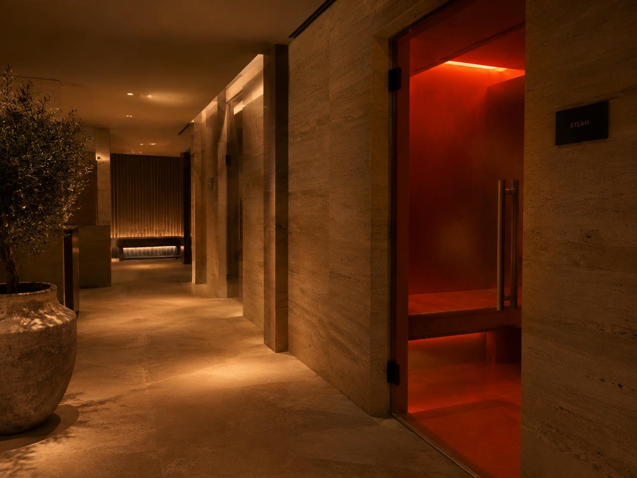 Travertine spa corridor with a red glass steam room door